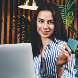 Pretty womanl using bonus card for online shopping. Young woman Pretty girl using bonus card for online shopping. Young woman paying for product bought on internet with debit bank card. Safe money transfer system at website of worldfamous retailer, quick shipping.