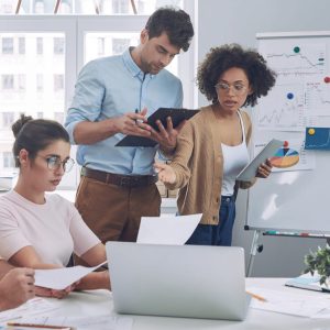 Group of confident young people in smart casual wear discussing business while having meeting in office Group of confident young people in smart casual wear discussing business while having meeting in office